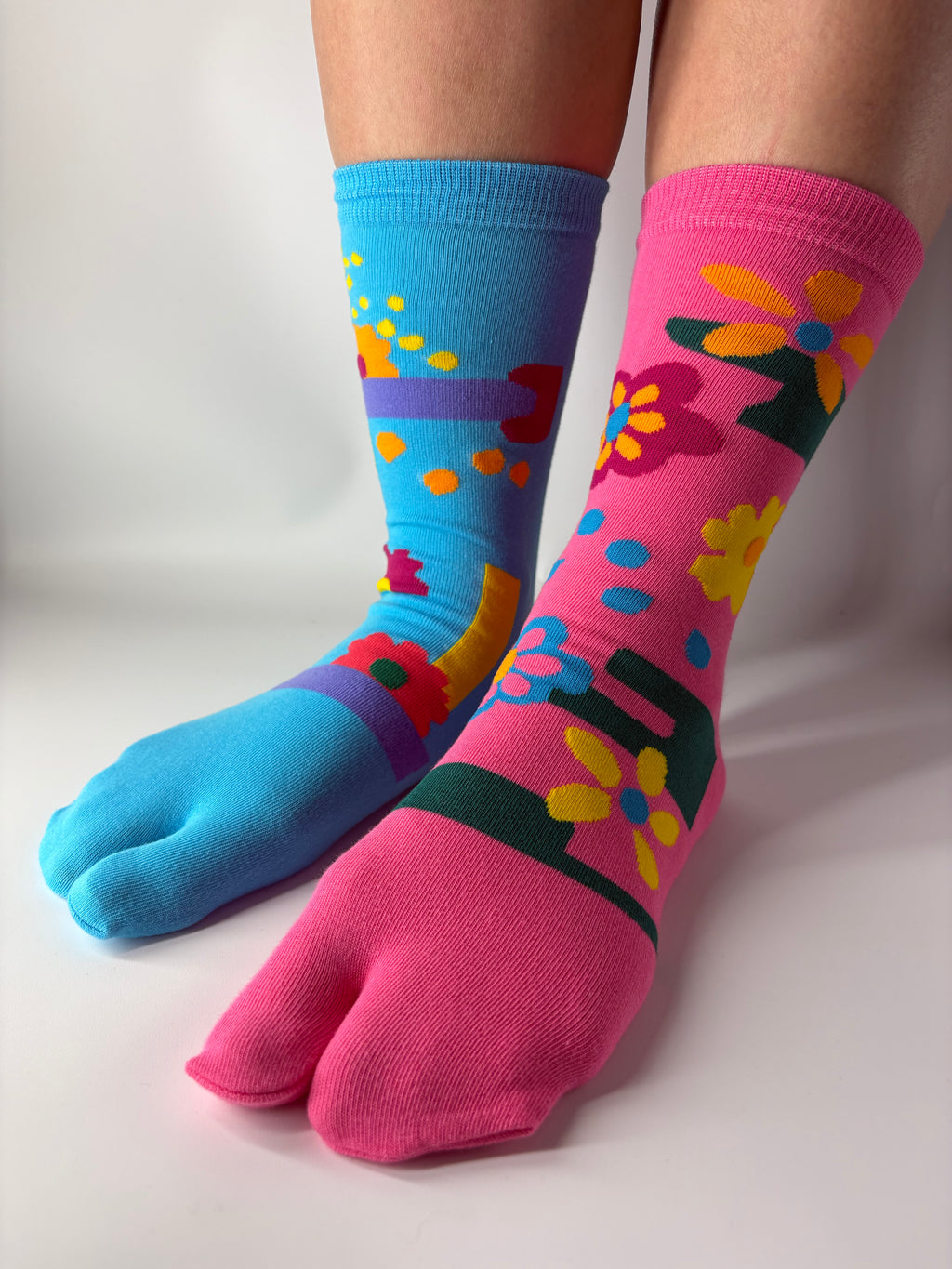 Tabi Co. split-toe cotton socks in sky blue and pink with a bright floral print, worn on feet