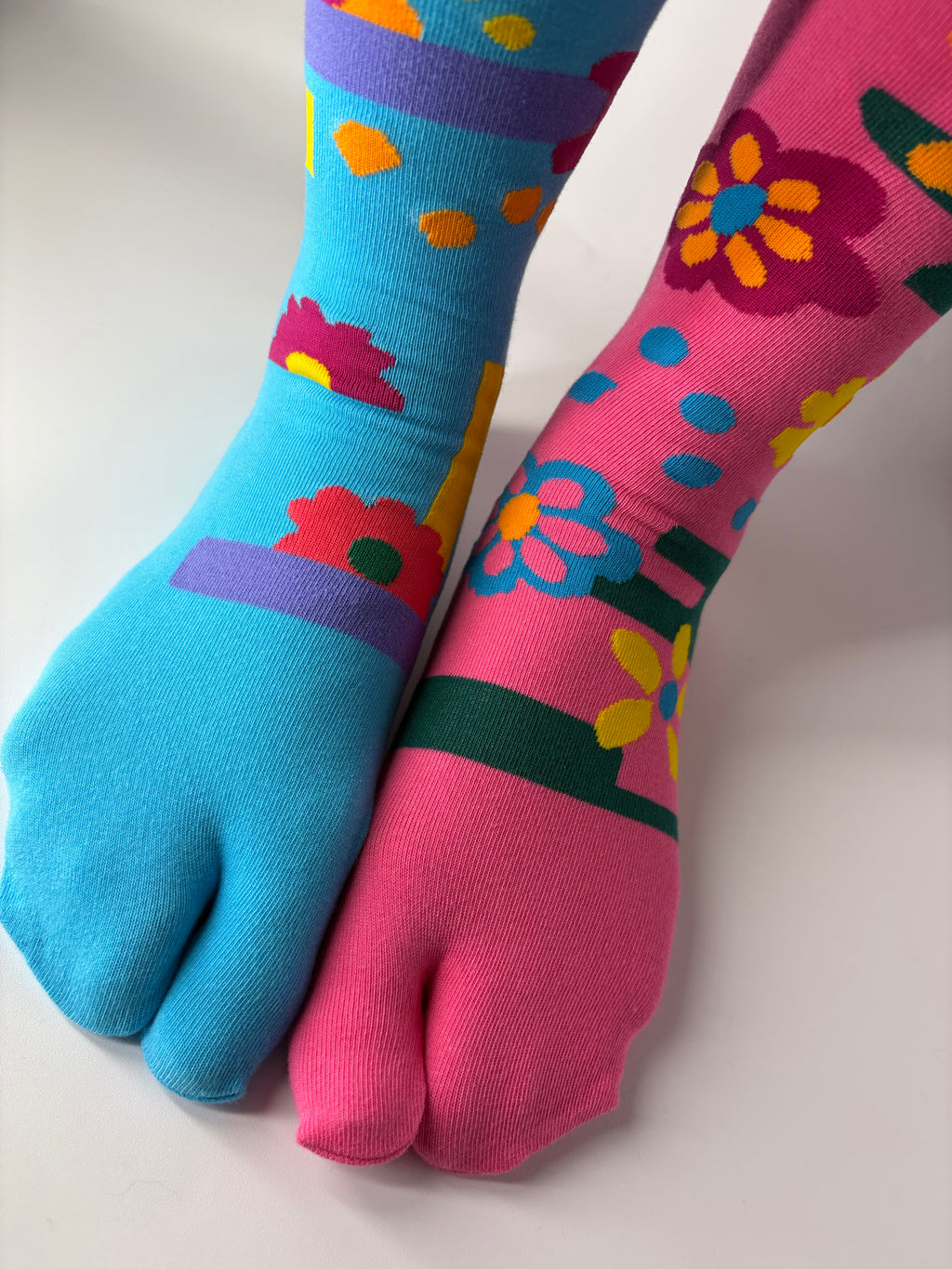 Tabi Co. split-toe cotton socks in sky blue and pink with a bright floral print, worn on feet