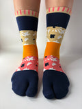 Tabi Co. patchwork tabi socks in navy, mustard, pink and khaki floral pattern, worn on legs against white background