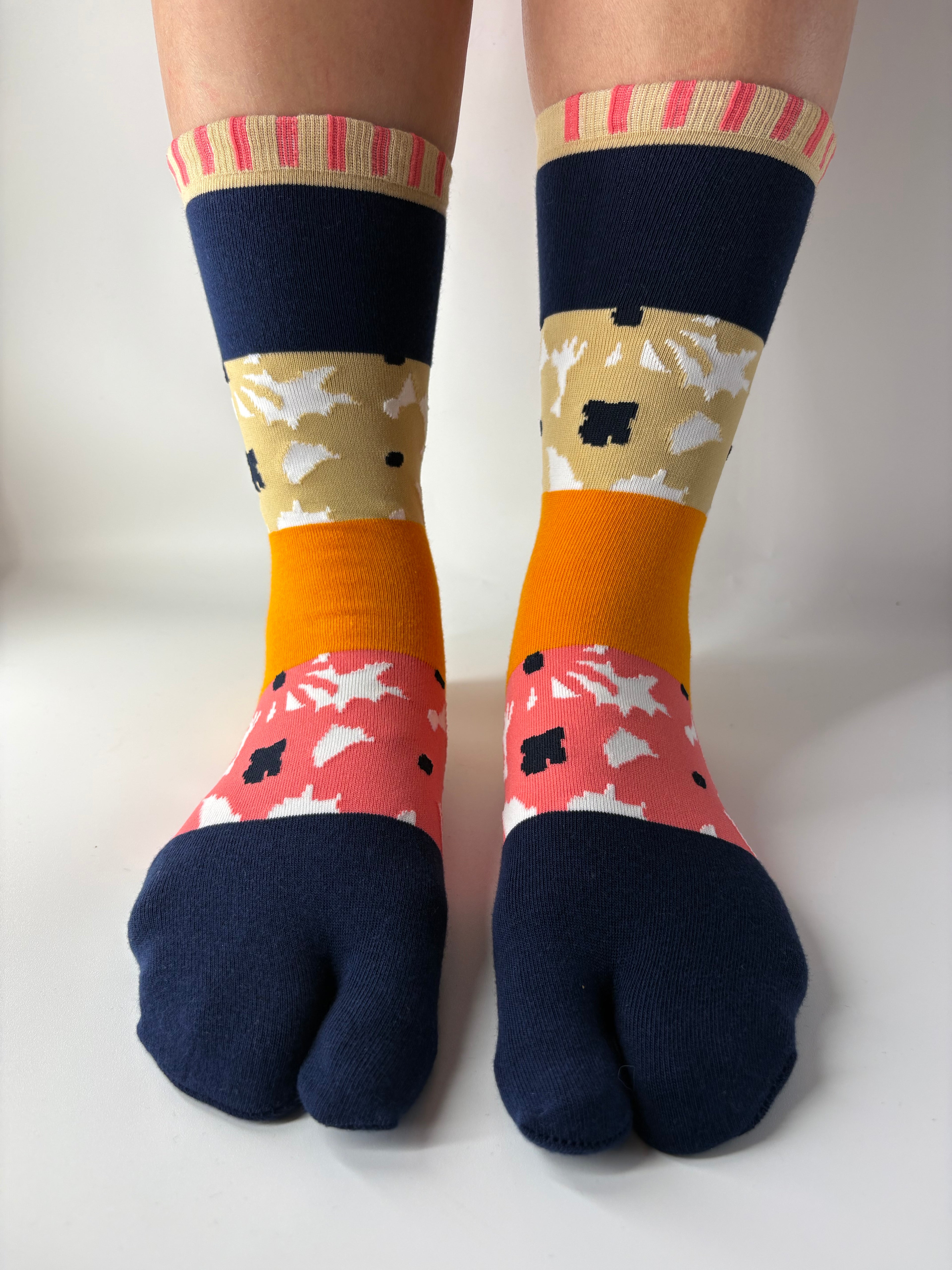Tabi Co. patchwork tabi socks in navy, mustard, pink and khaki floral pattern, worn on legs against white background