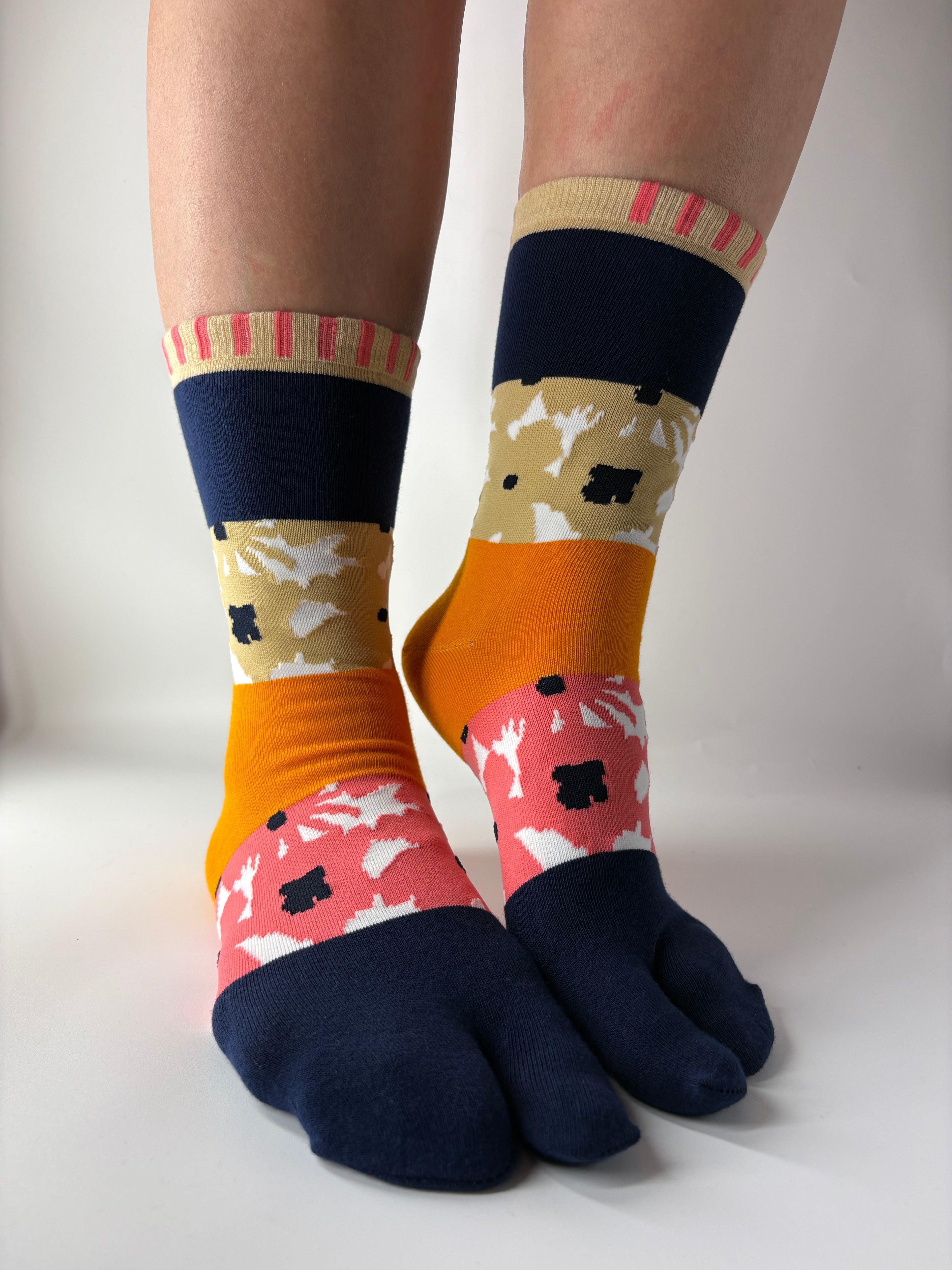 Colourblock abstract print on split toe tabi socks, model standing on white floor. 