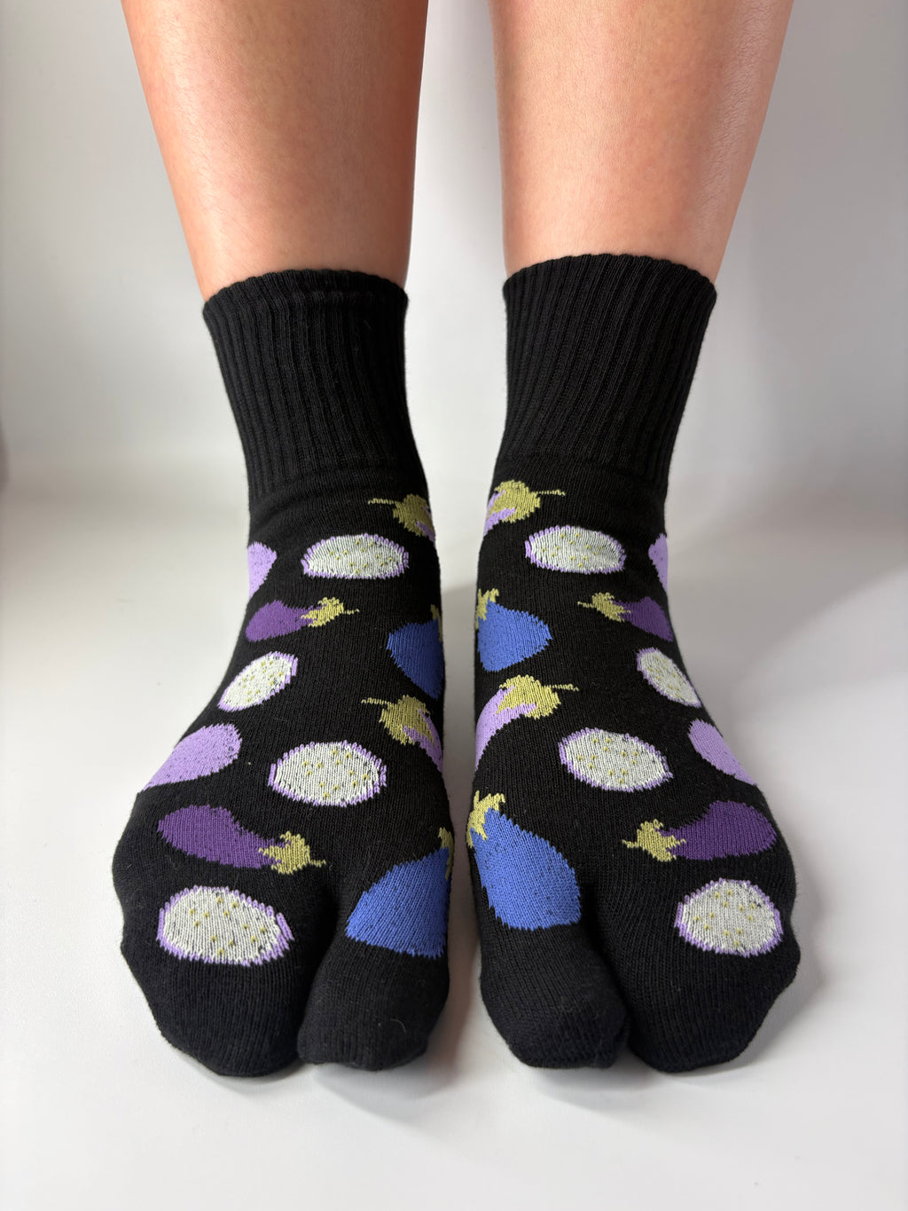 Black tabi short crew socks with colorful aubergine eggplant vegetable illustrations patterned on a white background