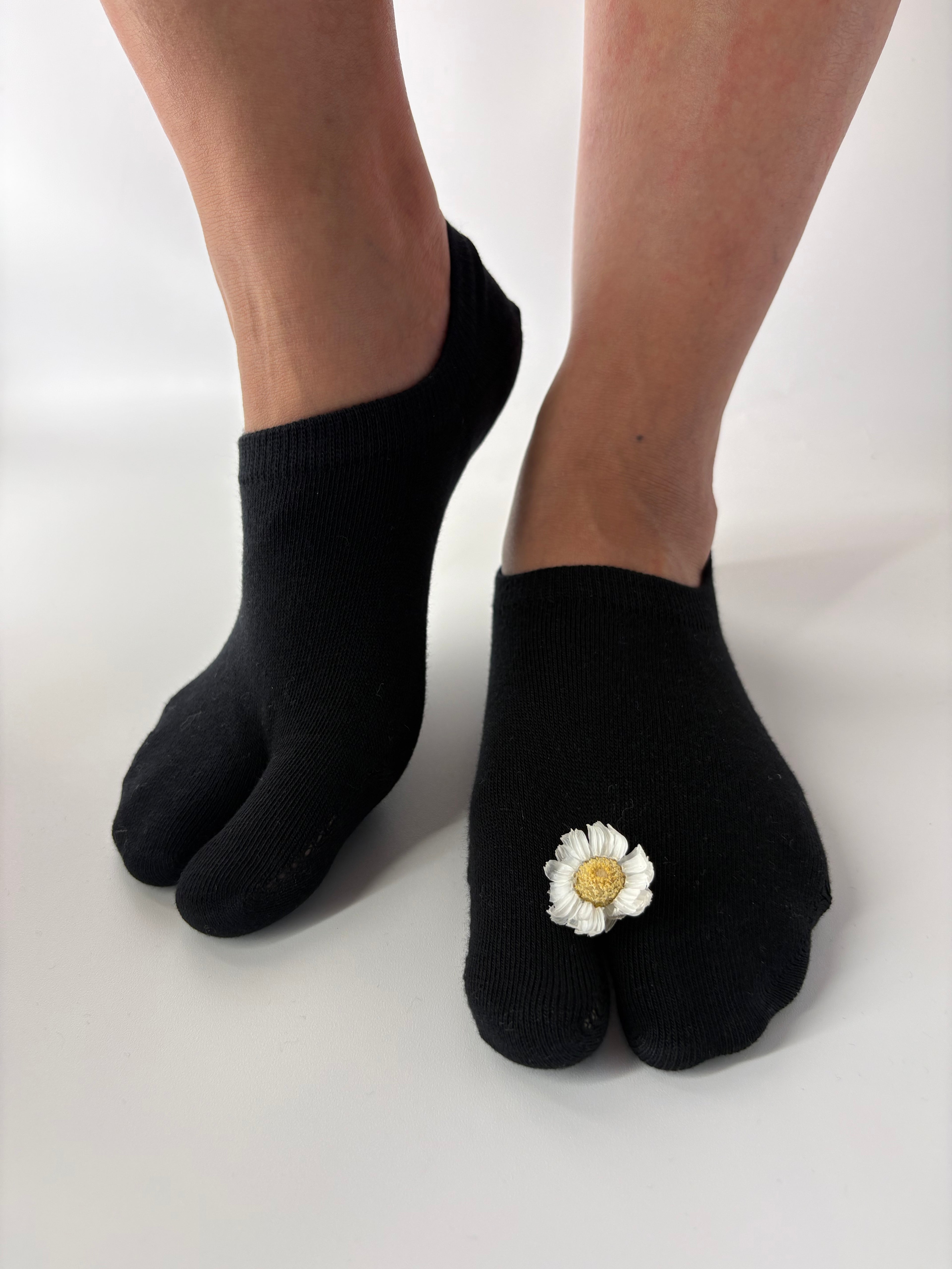 Black tabi socks with a white flower design on a white background
