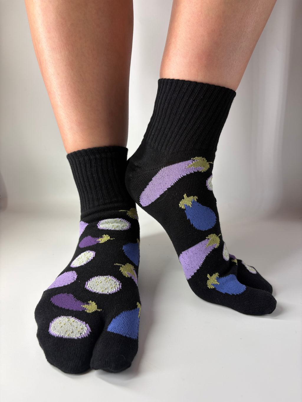 Black tabi short crew socks with colorful aubergine eggplant vegetable illustrations patterned on a white background made in japan