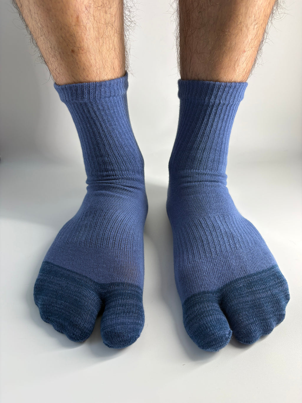 A pair of blue ribbed split-toe tabi socks worn on a person's feet, shown against a plain white background.