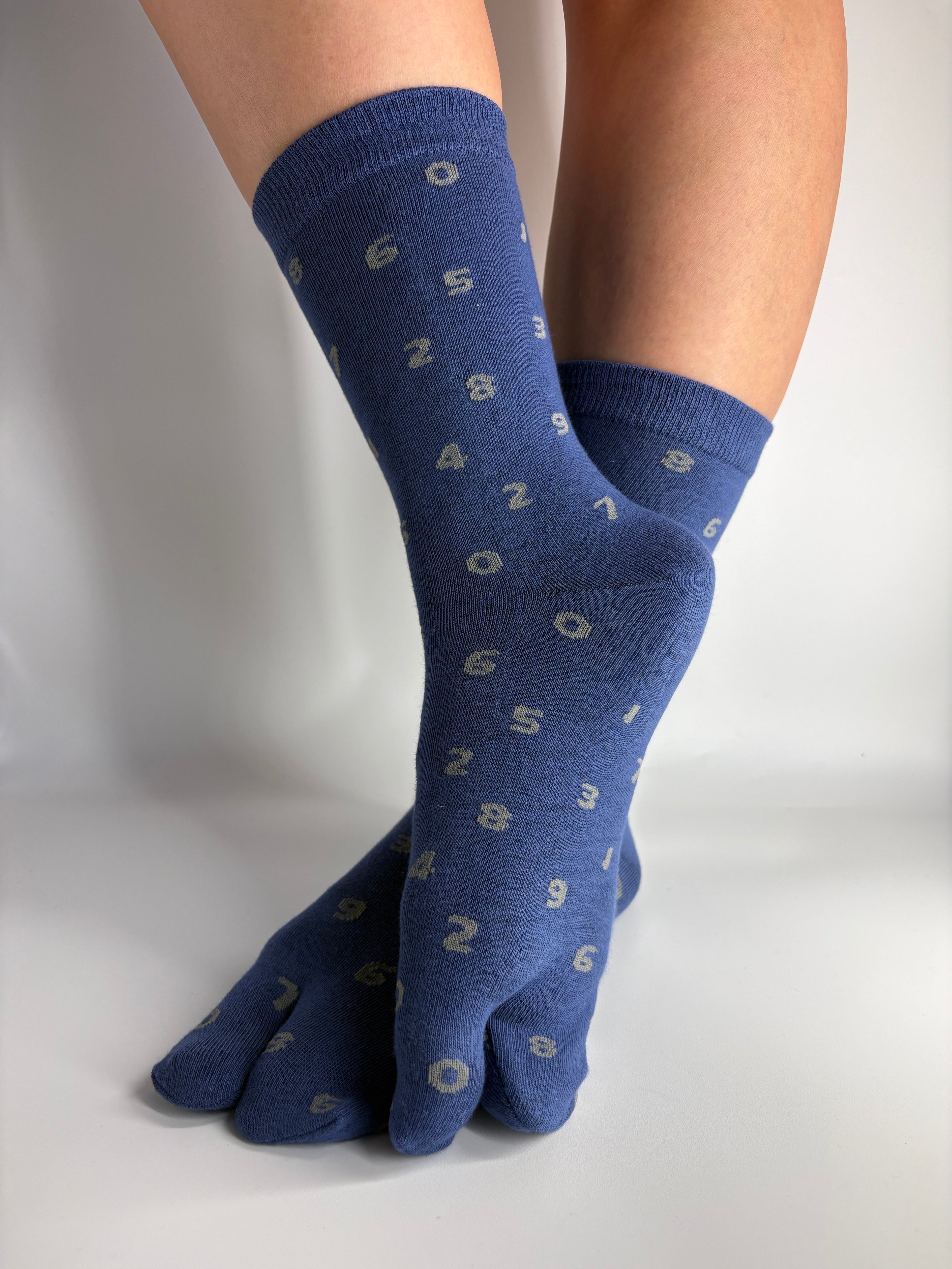 Denim blue crew length tabi socks with grey number print on, standing on a white background