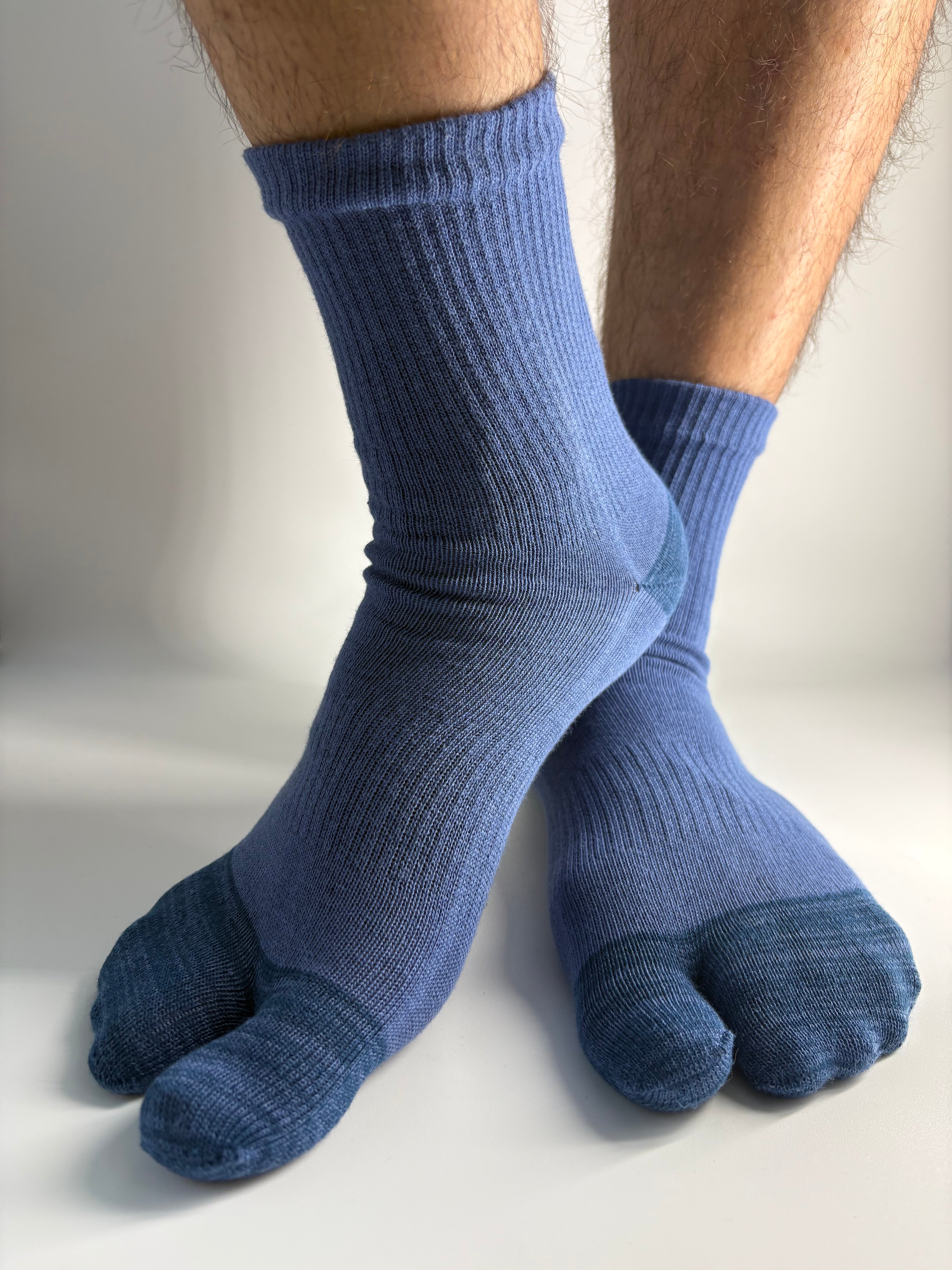A pair of ribbed blue toe socks worn on feet, shown against a plain light background.