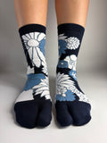 a navy blue and white flower print pair of tabi socks worn in a white studio