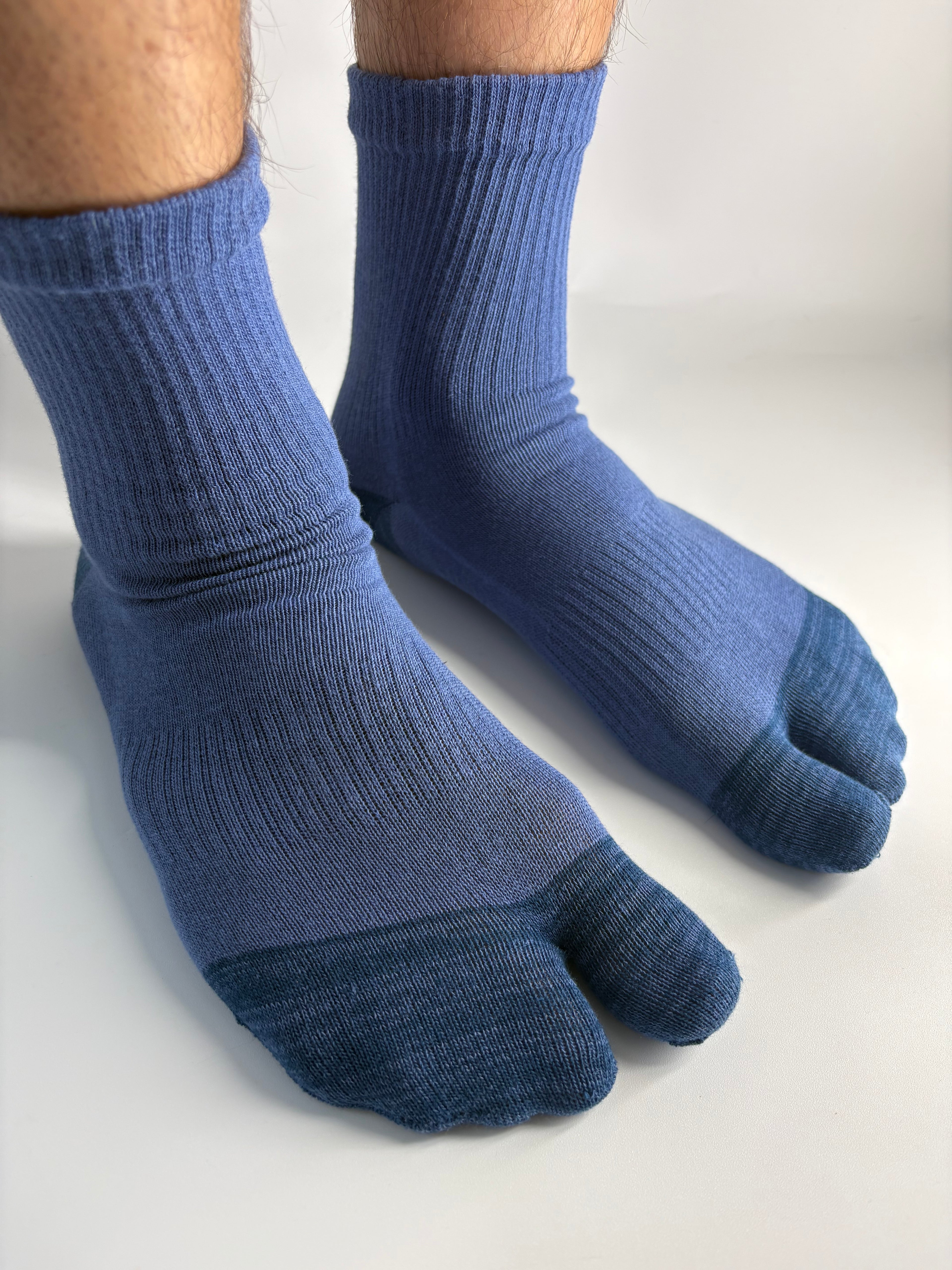 A pair of blue ribbed toe socks worn on feet, shown against a plain light background.