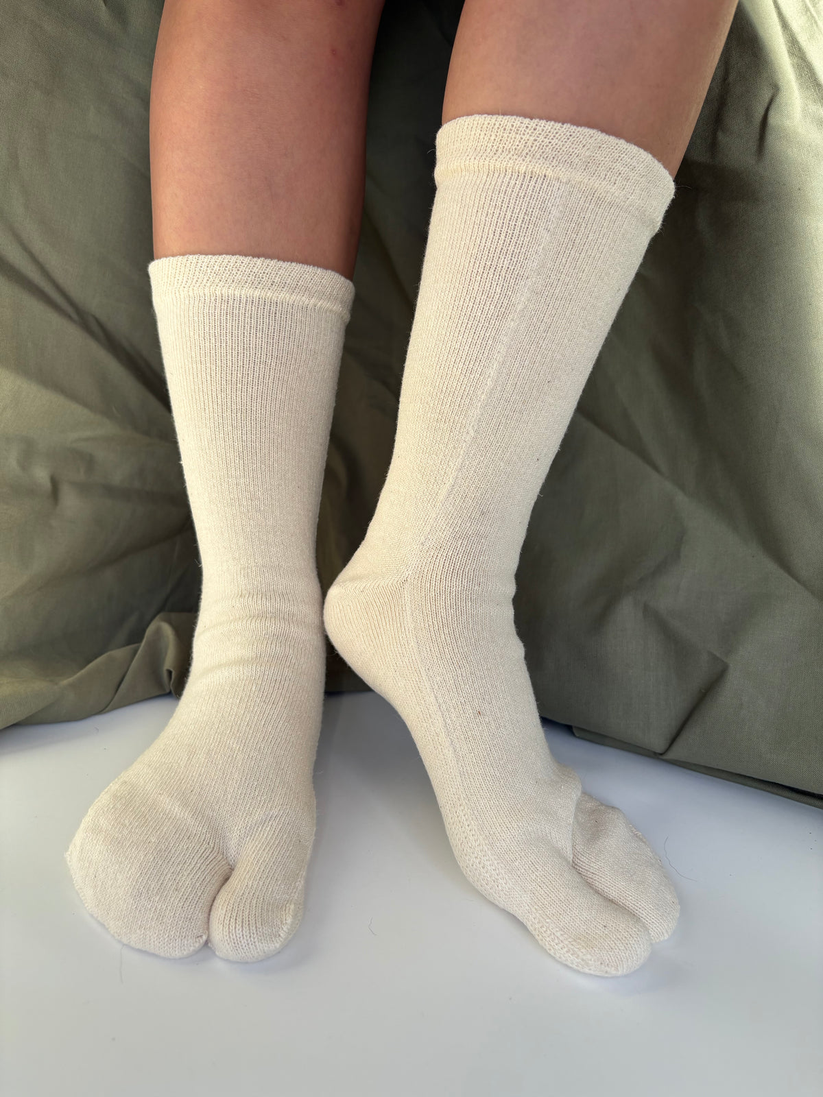 hemp socks mid calf height being worn on a persons foot with an olive green packground
