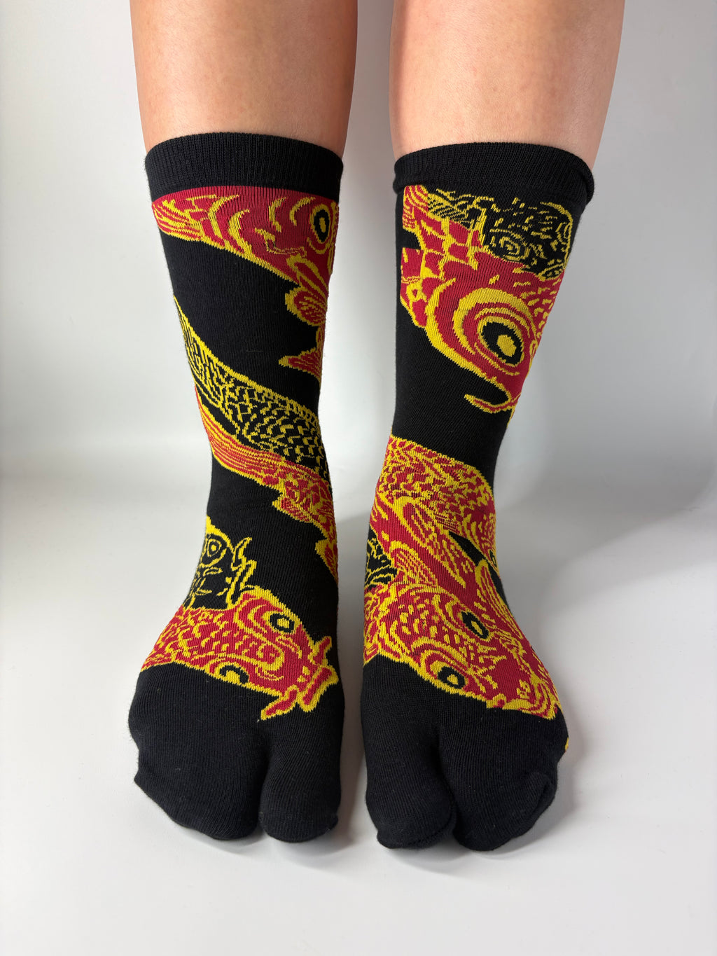 Black socks with red and yellow dragon design worn by a person on a white background