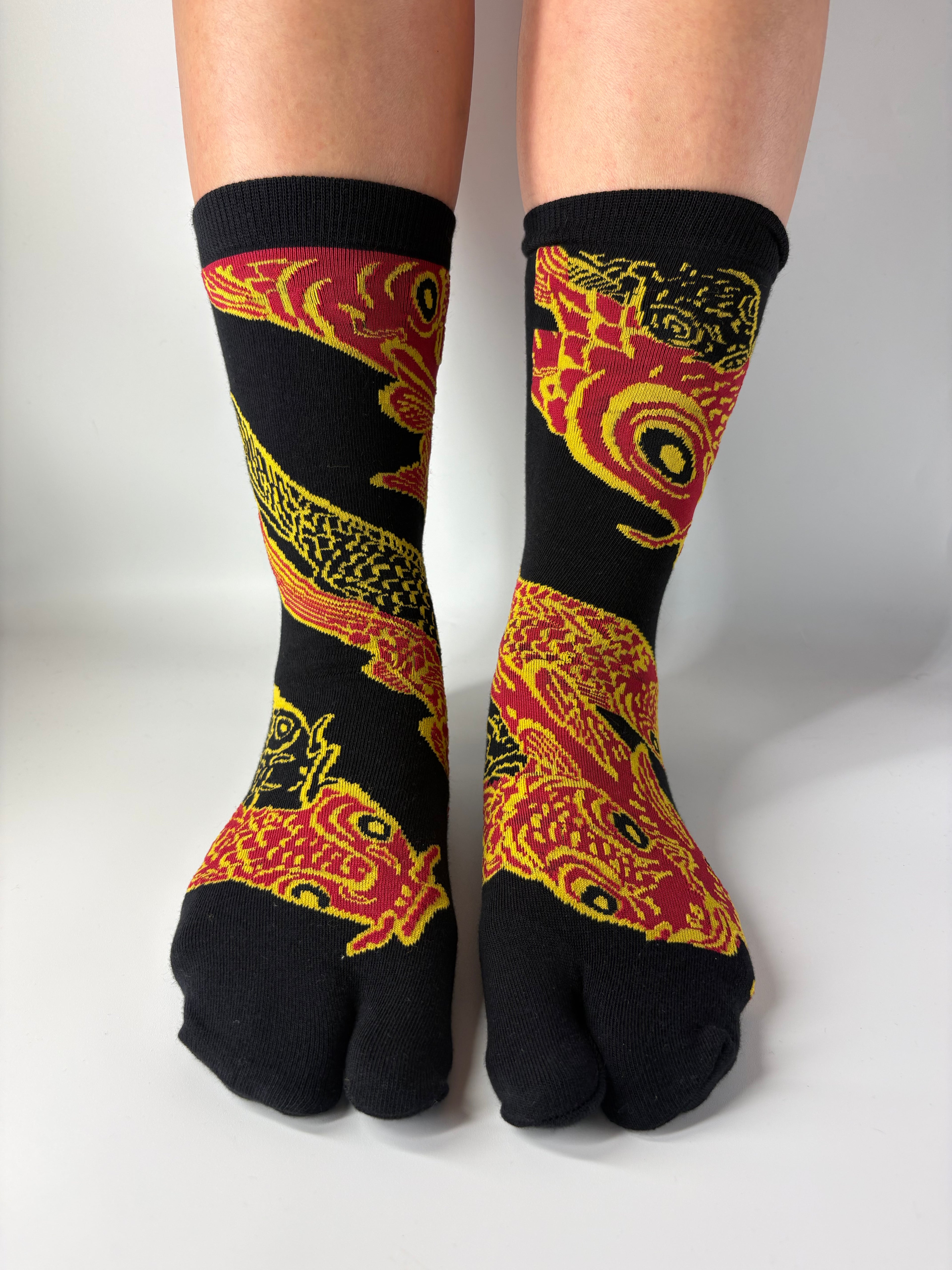 Black socks with red and yellow dragon design worn by a person on a white background