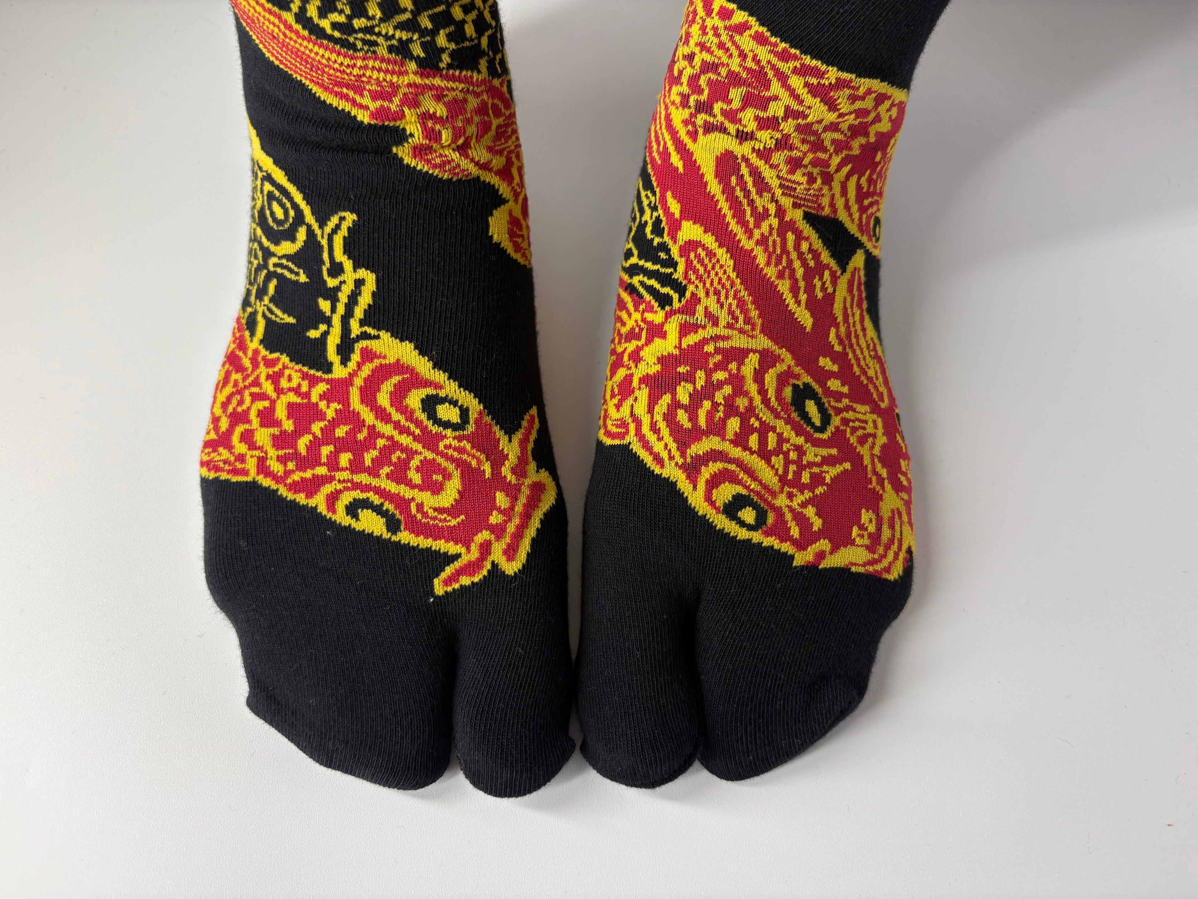 Black toe-separated socks with red and yellow patterns on a white background