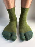 A pair of green ribbed split-toe socks worn on a person's feet, shown against a plain light background.