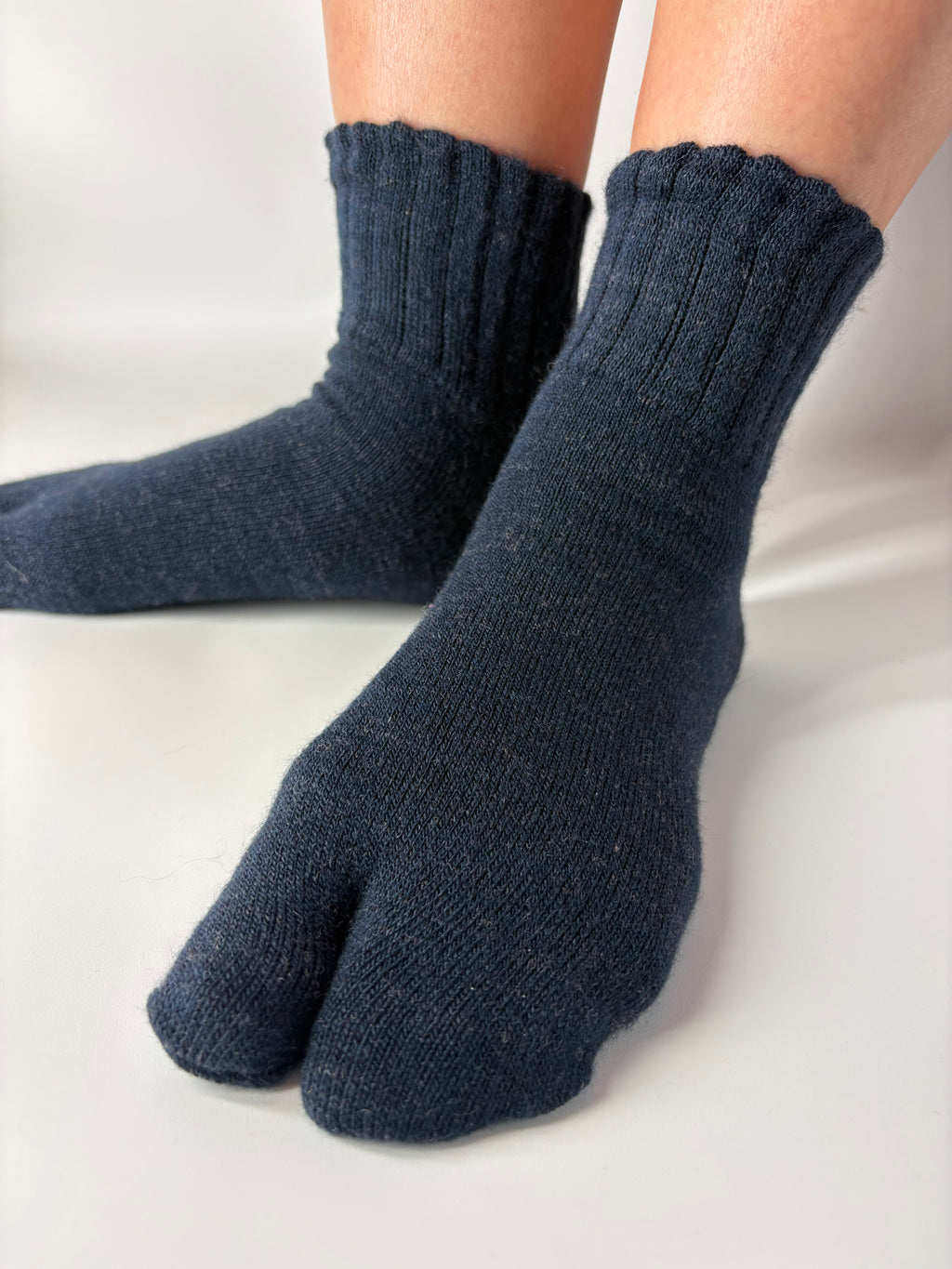 Dark blue socks being worn on a light background