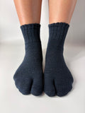 Pair of dark blue wool tabi socks worn on a white background