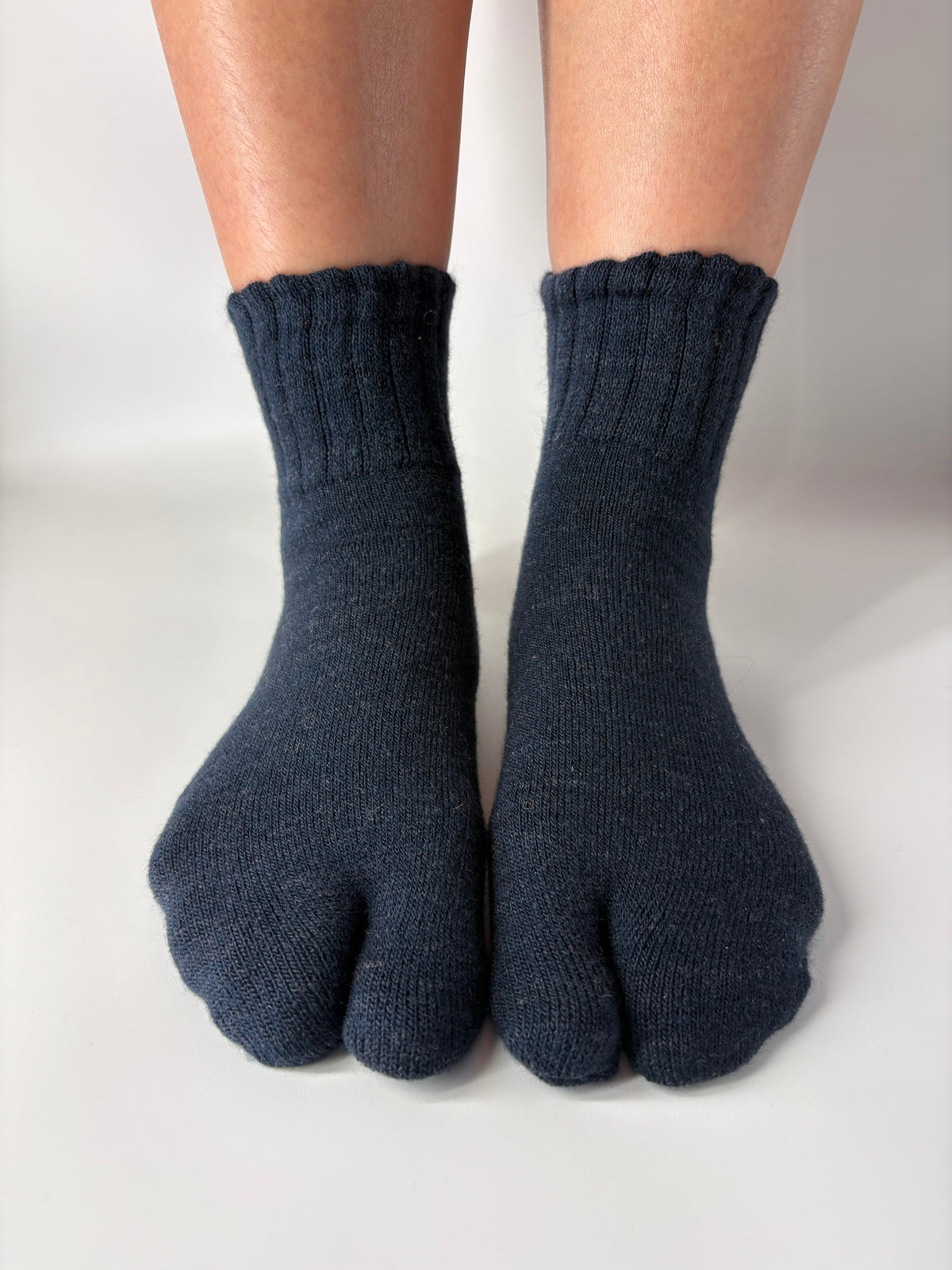 Pair of dark blue wool tabi socks worn on a white background