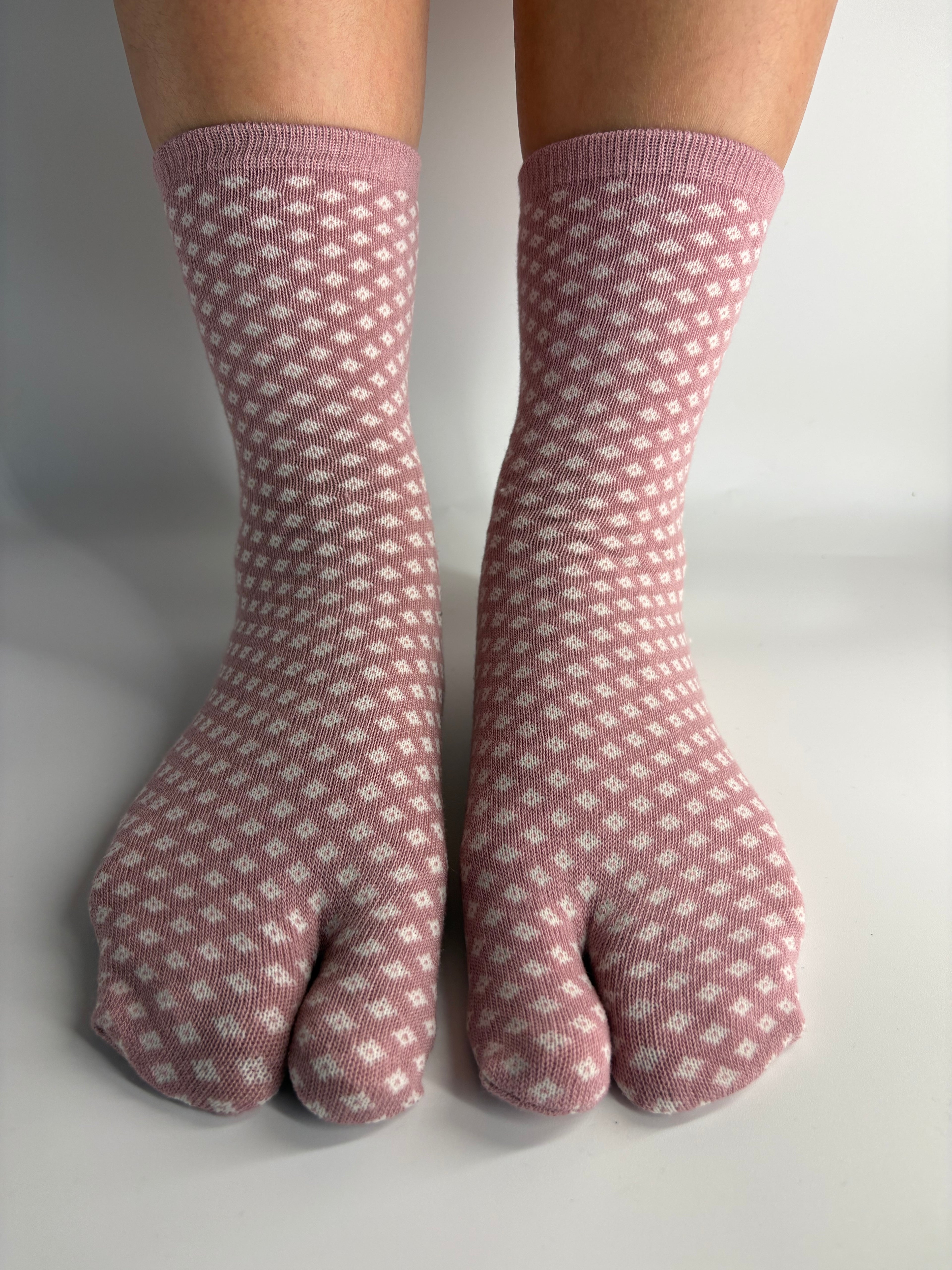 Pink and white patterned tabi socks worn on a person's feet, shown against a plain light gray background.