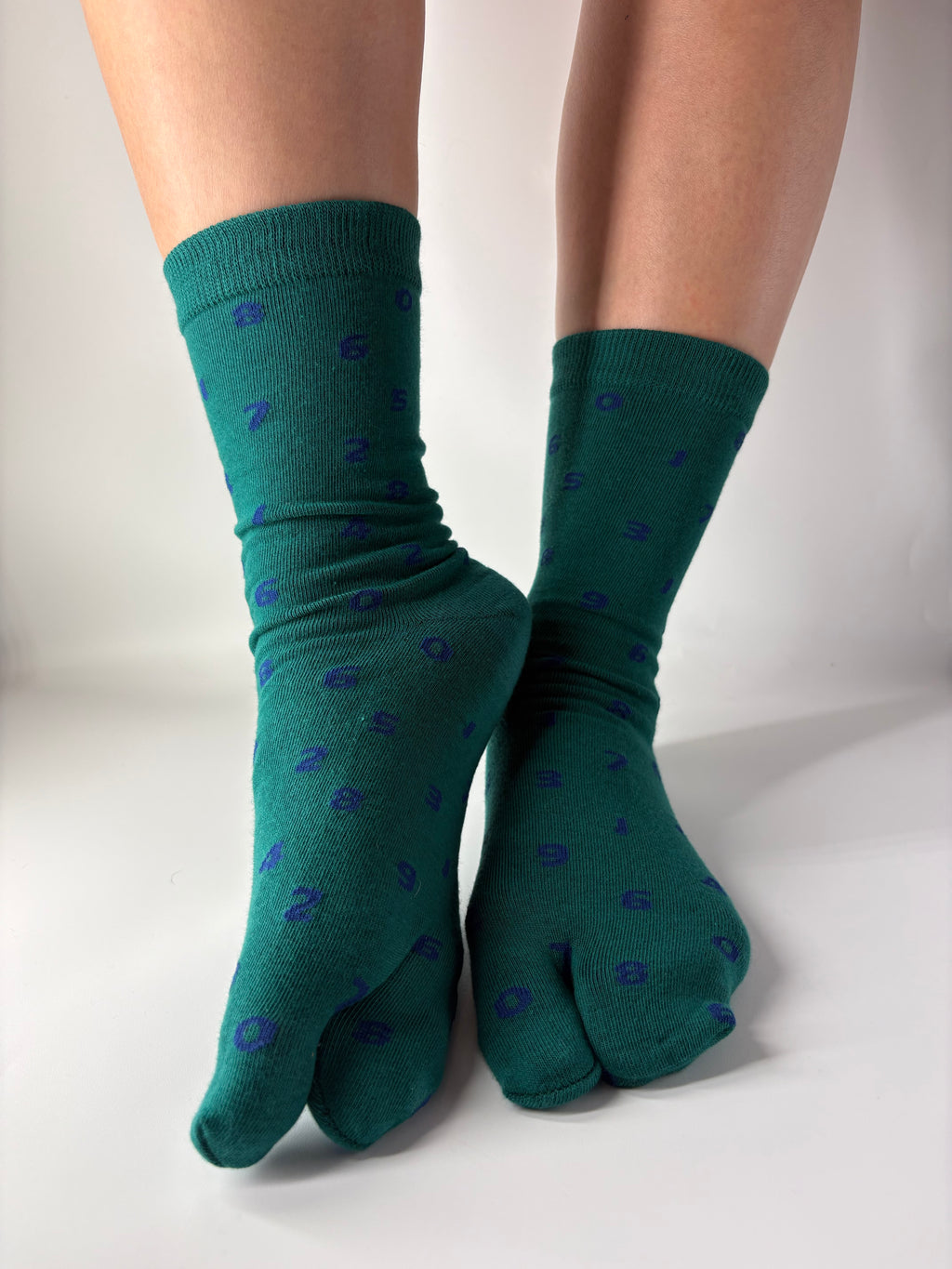 Tabi Co. teal split-toe cotton socks with a scattered blue number print, worn on feet
