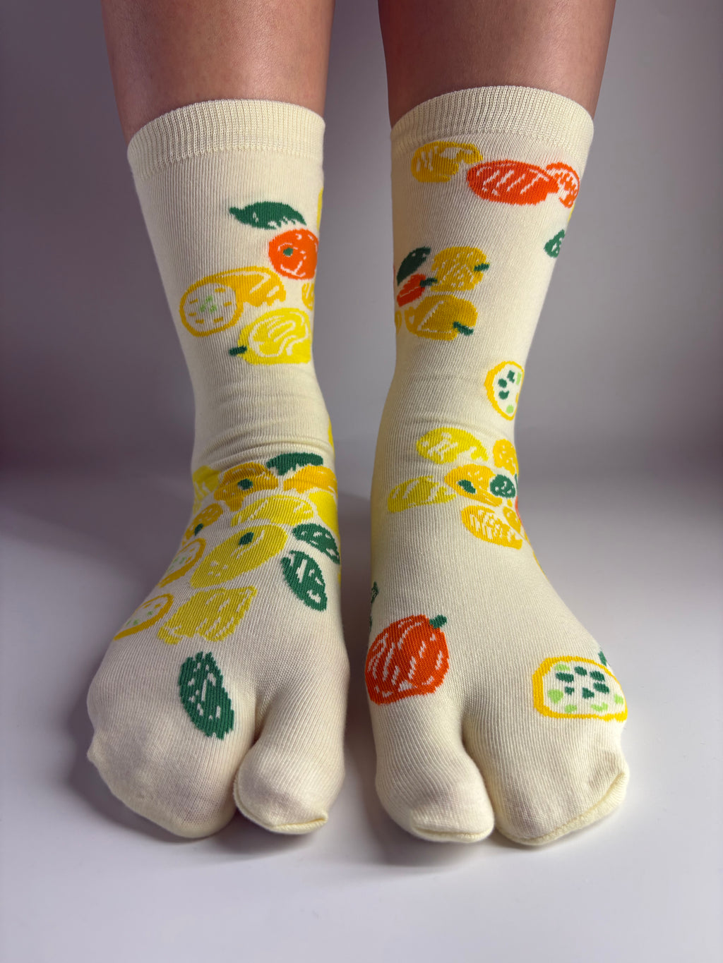 Pair of light yellow tabi socks with a lemon citrus fruit print
