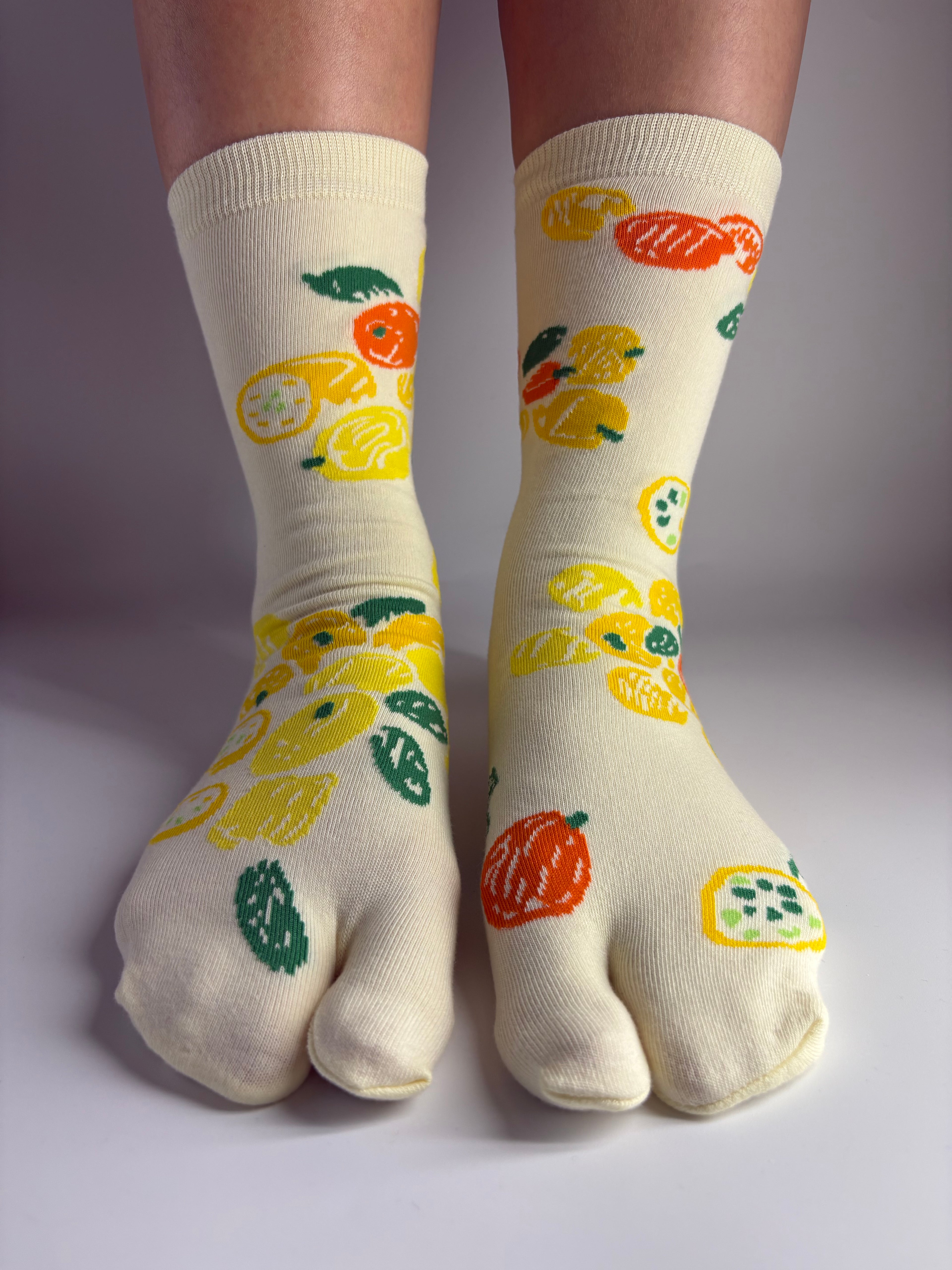 Pair of light yellow tabi socks with a lemon citrus fruit print